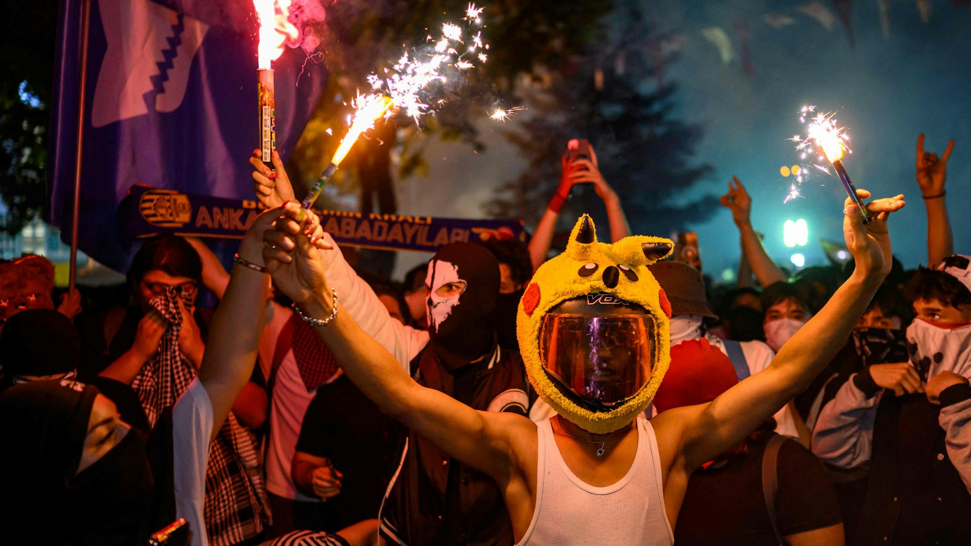 A protester in a pikachu hat holds a firecracker during a rally protesting the 100th day of the detention of Istanbul Mayor Ekrem Imamoglu, at Sarachane Square in Istanbul, on July 1, 2025. (Photo by Yasin AKGUL / AFP)