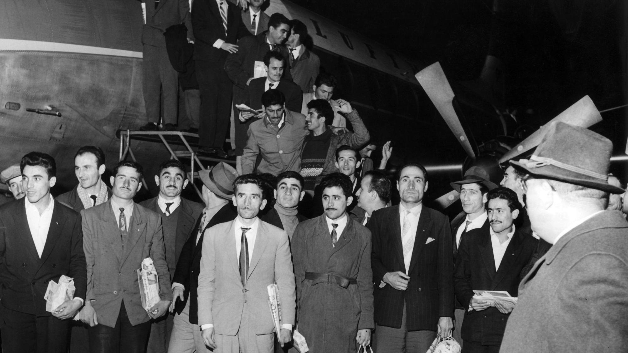55 Gastarbeiter steigen aus einem Flugzeug.