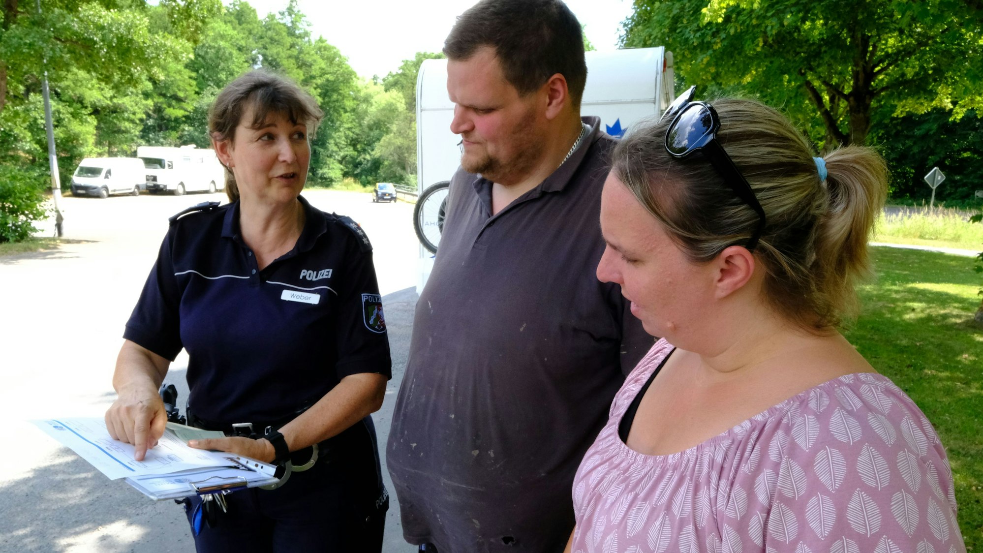 Die Eheleute Schallenberg im Gespräch mit Polizeibeamtin Anke Weber. Im Hintergrund ist ein Wohnanhänger zu erkennen.