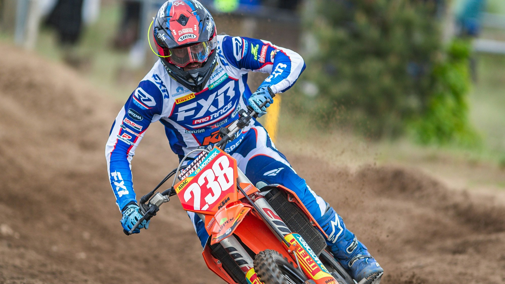 Zu sehen ist ein Motocross-Fahrer der durch den Schlamm fährt.