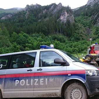 Einsatzfahrzeuge von Polizei, Feuerwehr und Bergrettung stehen am Berg.