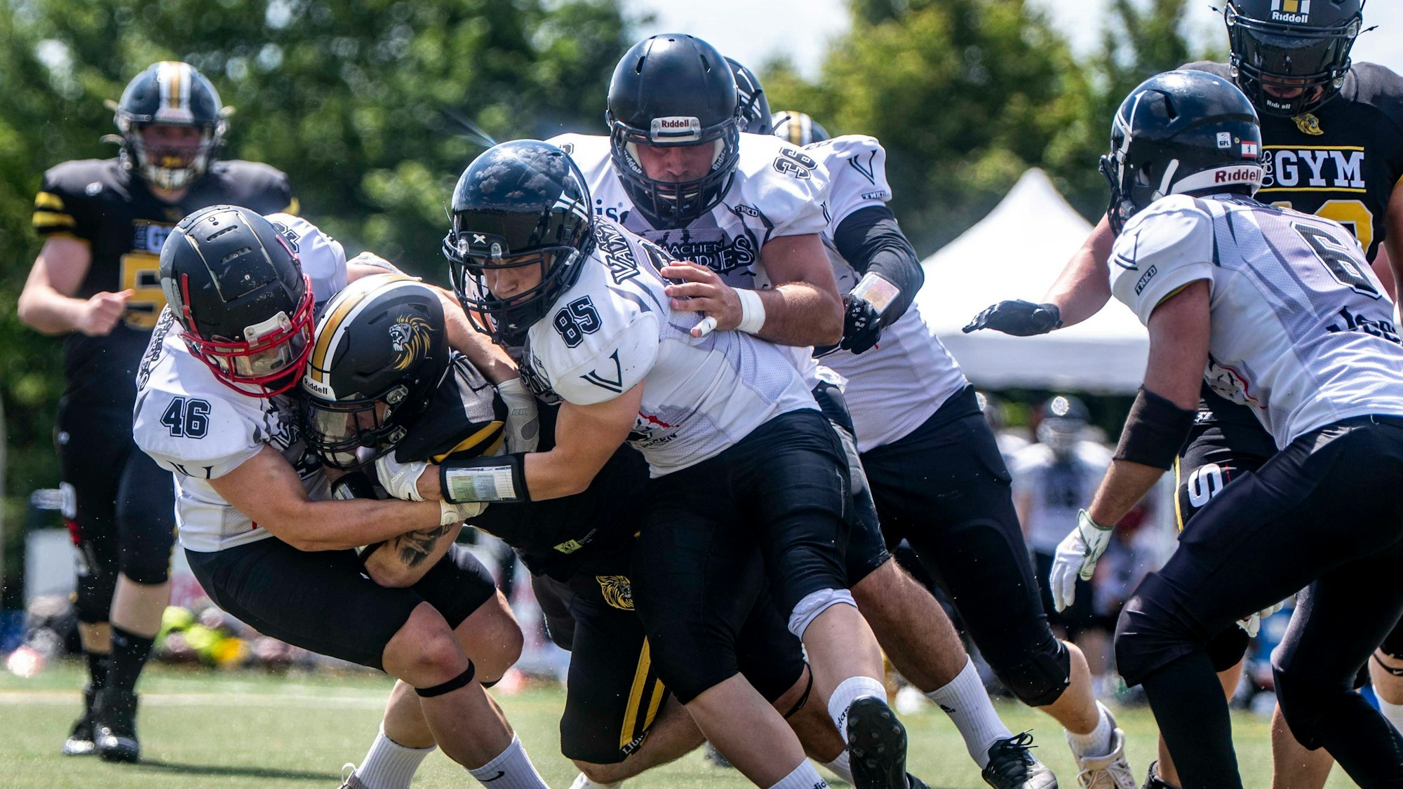 Footballspieler ringen um den Ball. Die Sonne reflektiert von einigen der Helme.