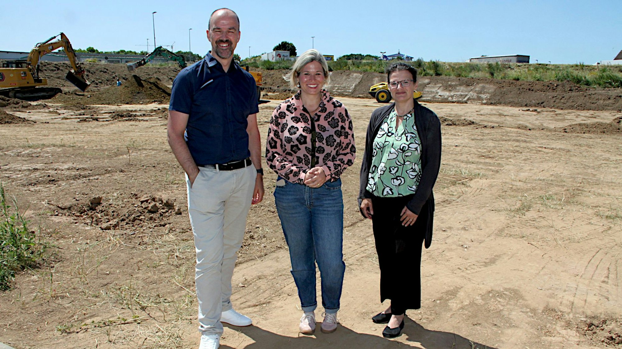 Blankenheims Bürgermeisterin Jennifer Meuren, Guido Waters, Wirtschaftsförderer der Gemeinde, und Carmen Heyner (Co-Teamleitung Gemeindeentwicklung) stehen an der Baustelle der neuen McDonalds-Filiale im erweiterten Industrie- und Gewerbegebiet oberhalb von Blankenheim.