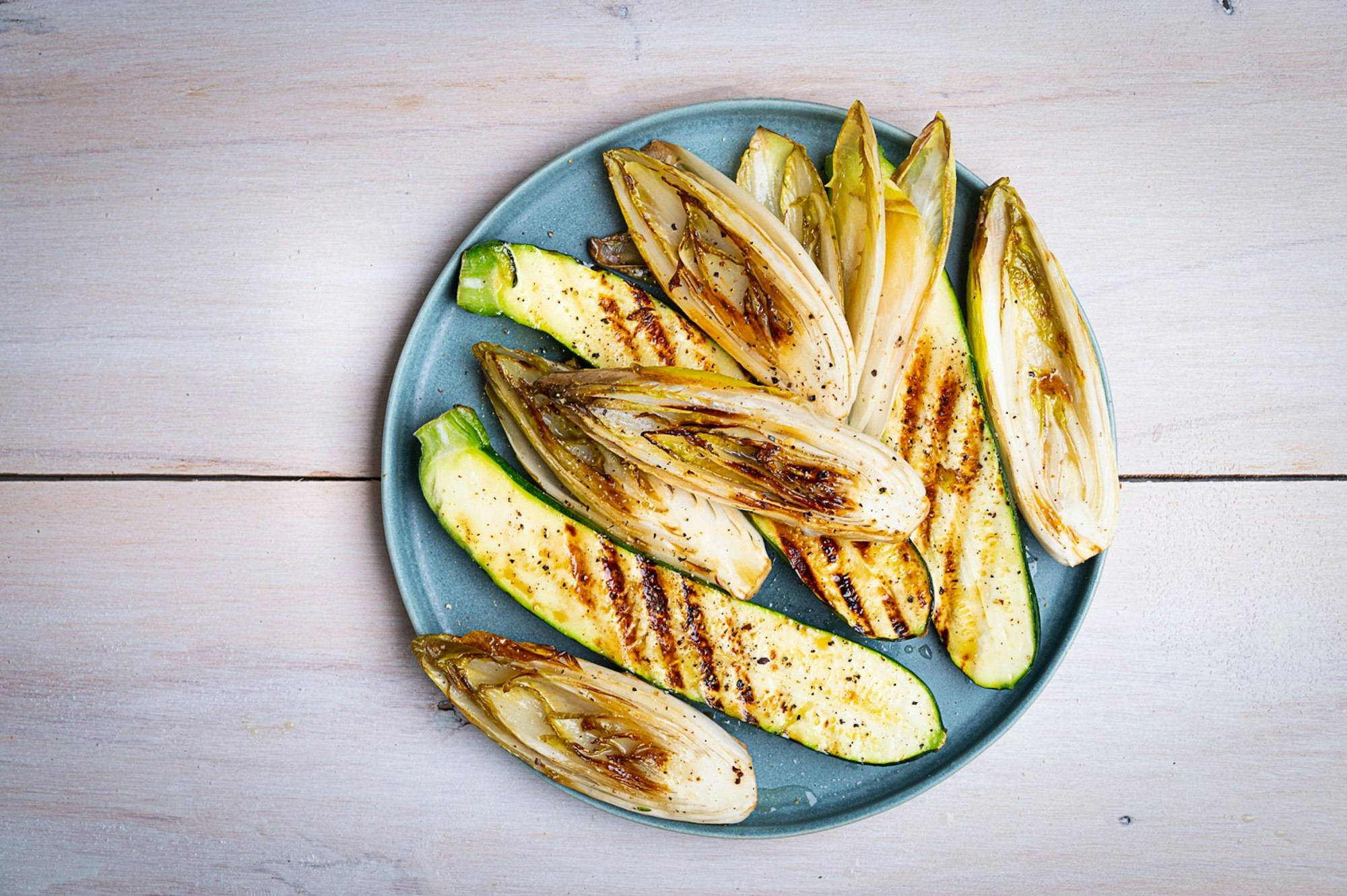 Die länglich geschnittenen Zucchini- und Chicorée-Streifen werden mit einer Marinade aus Olivenöl, Limettensaft, Salz und Pfeffer eingepinselt, dann auf jeder Seite 2–3 Minuten gegrillt.