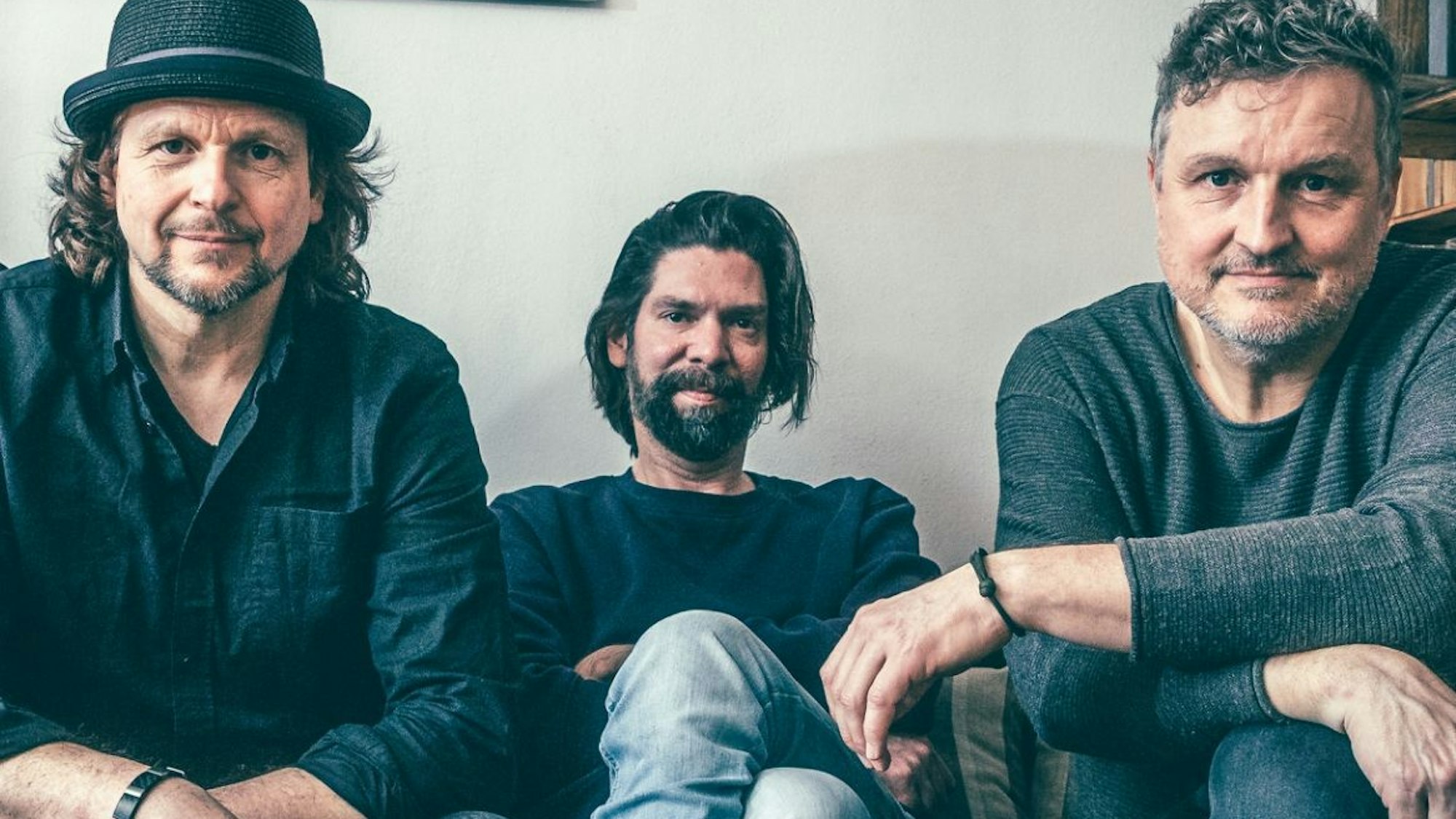 Die drei Bandmitglieder Robert Schuller, Sebastian Demmin und Volker Rechin sitzen nebeneinander.