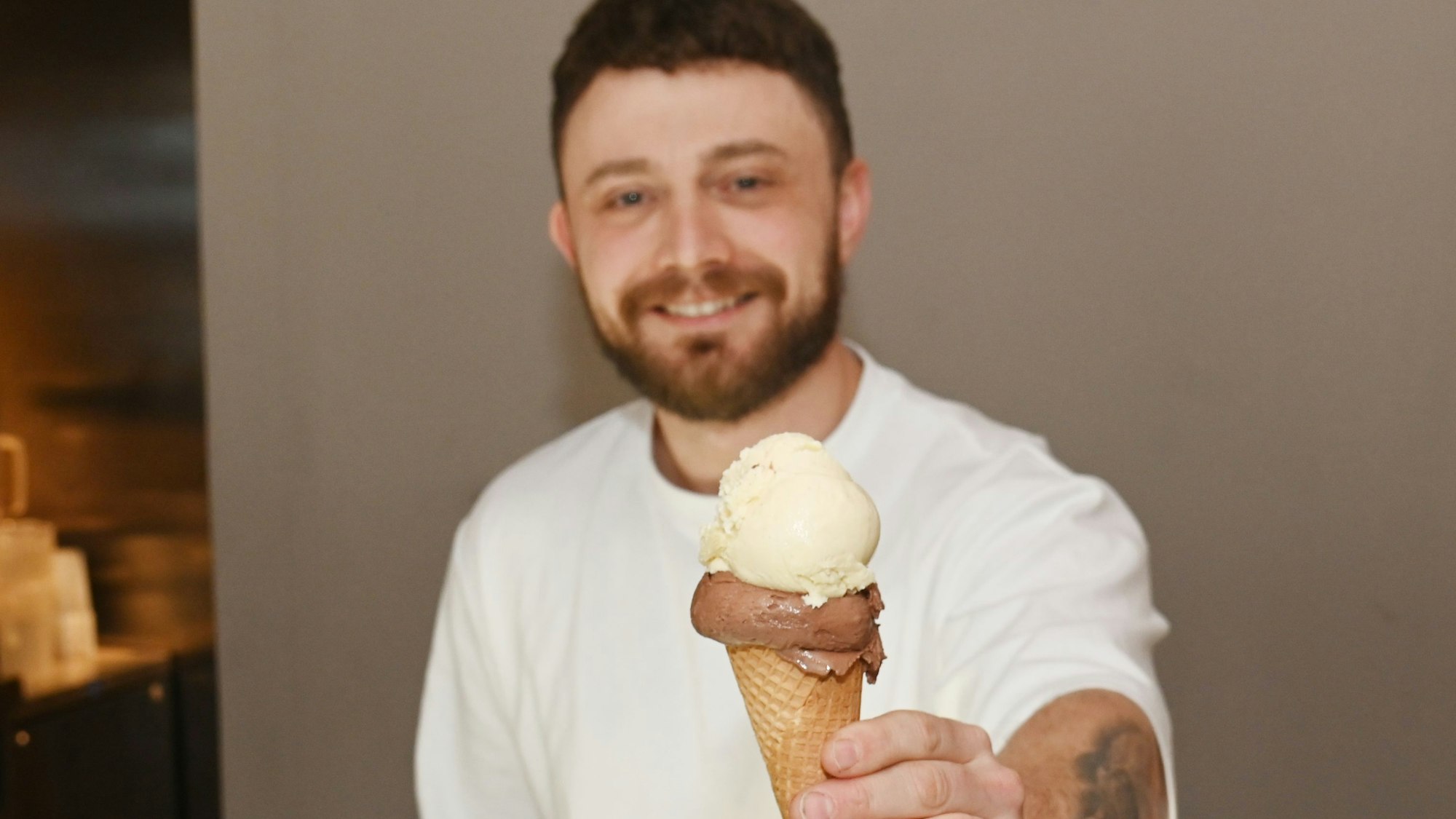 Ein Mann hält ein Eis mit zwei Kugeln in der Hand.