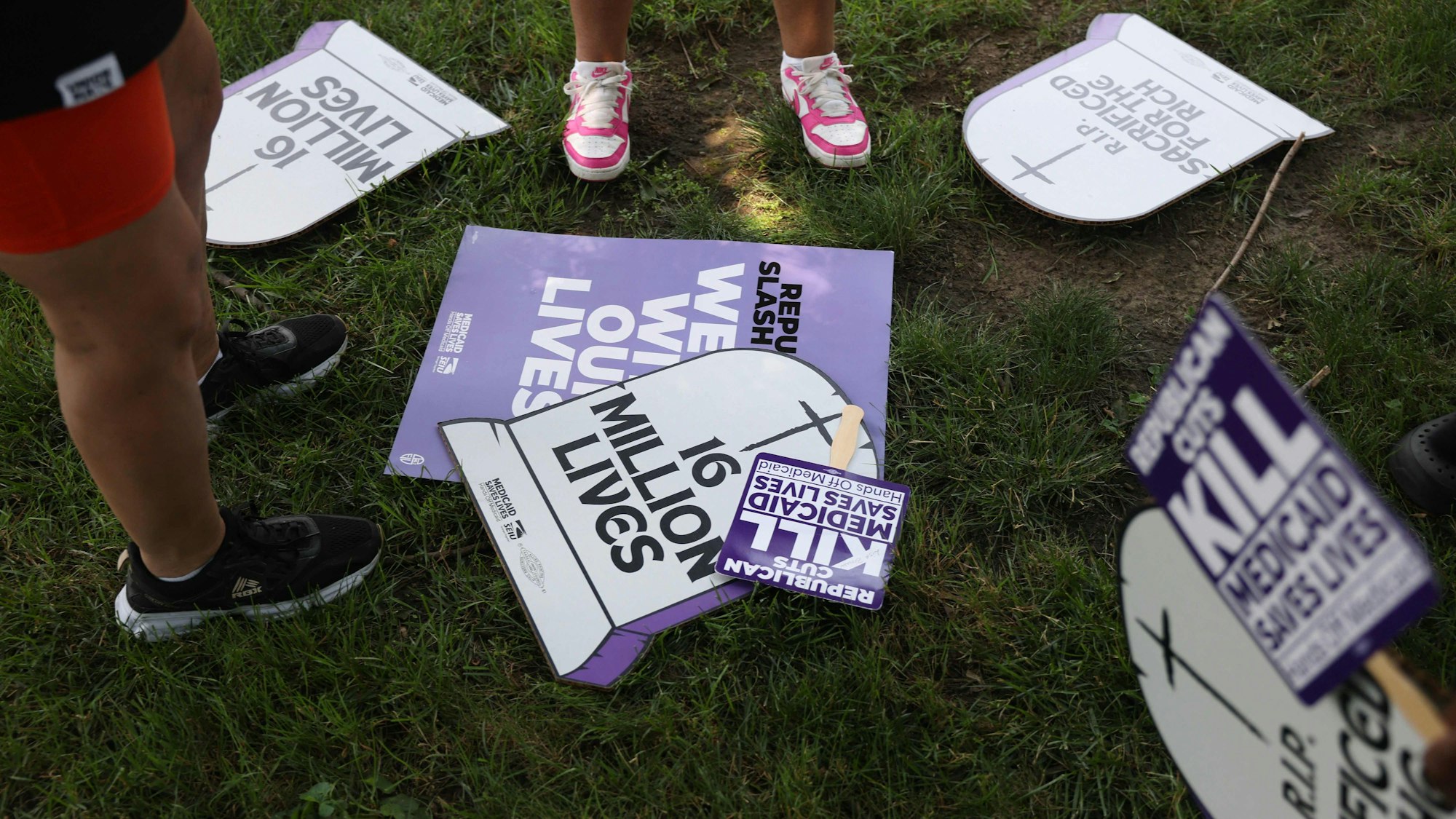 Schilder einer Demonstration gegen die Sozialkürzungen liegen auf einer Wiese in Washington.