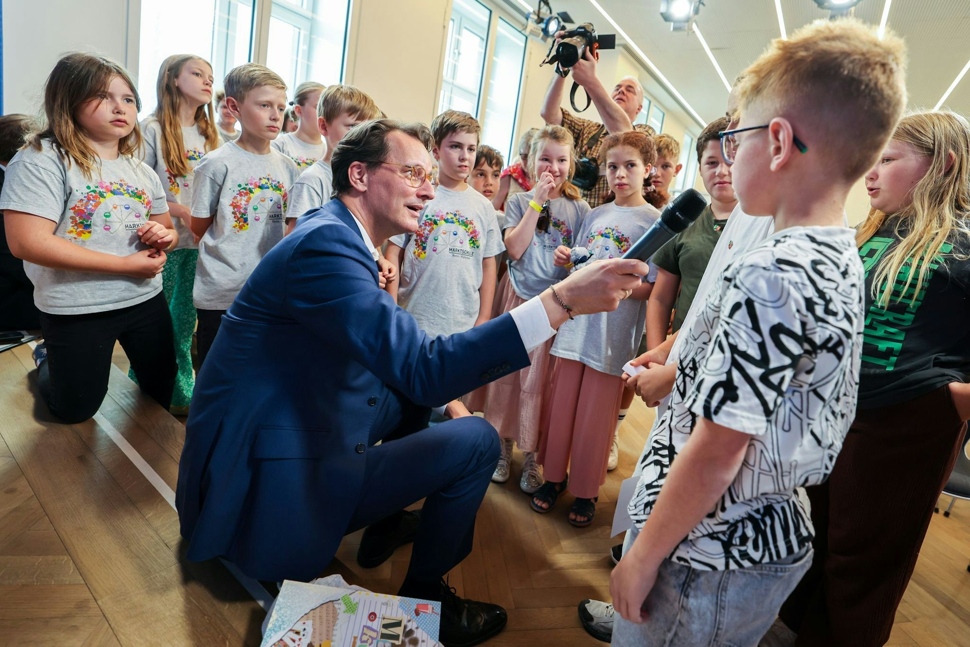 NRW-Ministerpräsident Hendrik Wüst (CDU) hält bei Fragen der Kinderreporter auch mal selbst das Mikrofon.