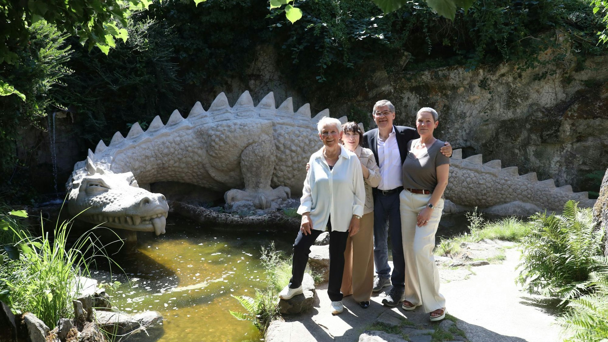 Vier Personen vor einer Steinskulptur, die einen Drachen darstellt.