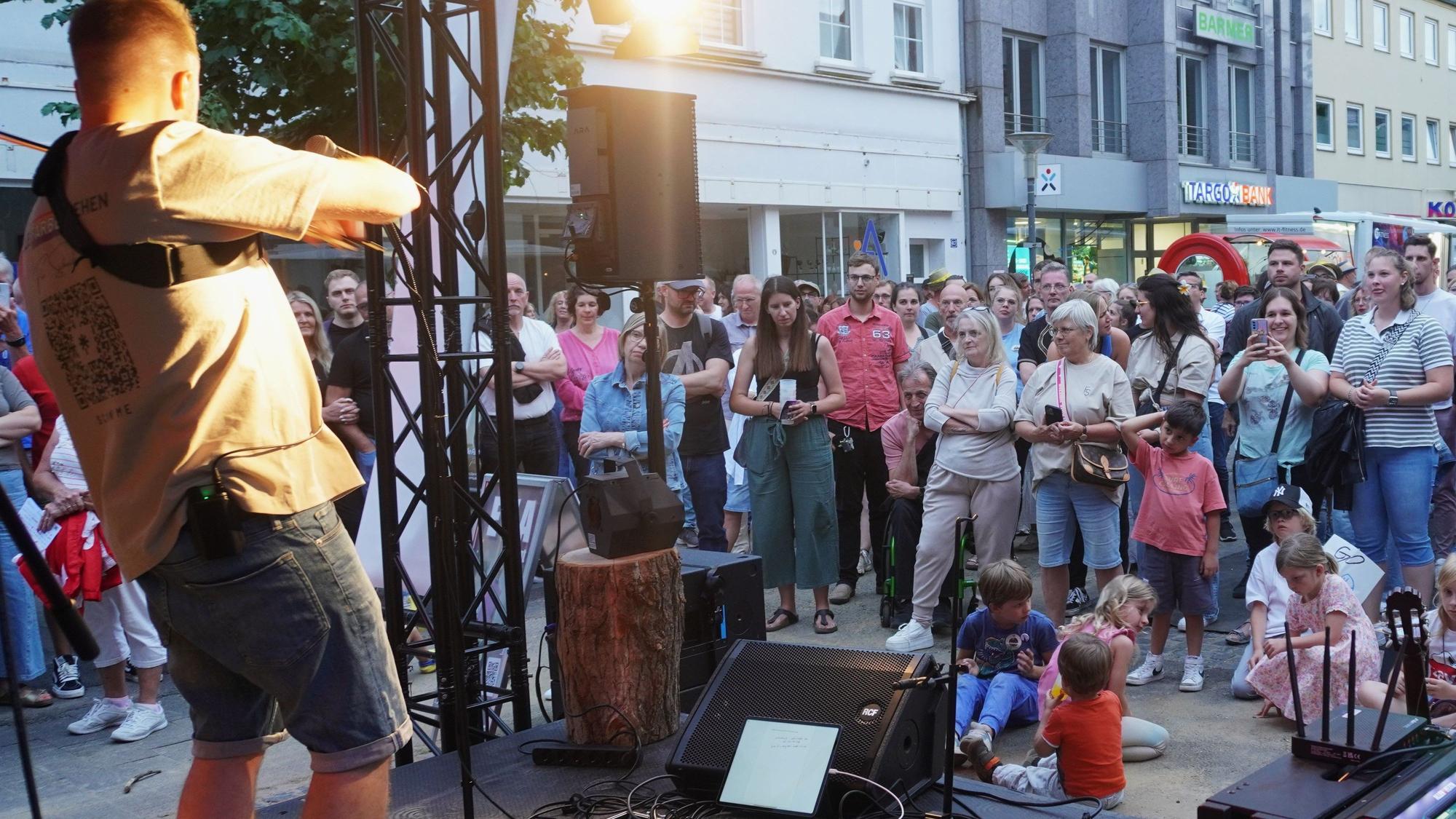 Vor einer Bühne lauscht das Publikum den Songs von Florian Scholdan.