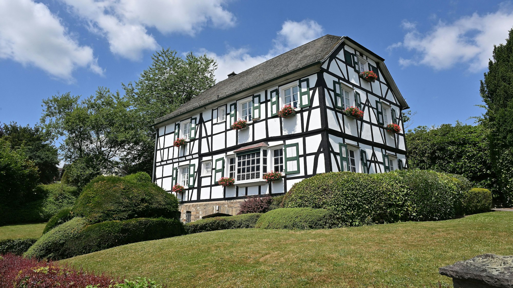 Das Alte Pastorat, ein historisches Fachwerkhaus, ist umringt von Hecken und Büschen.