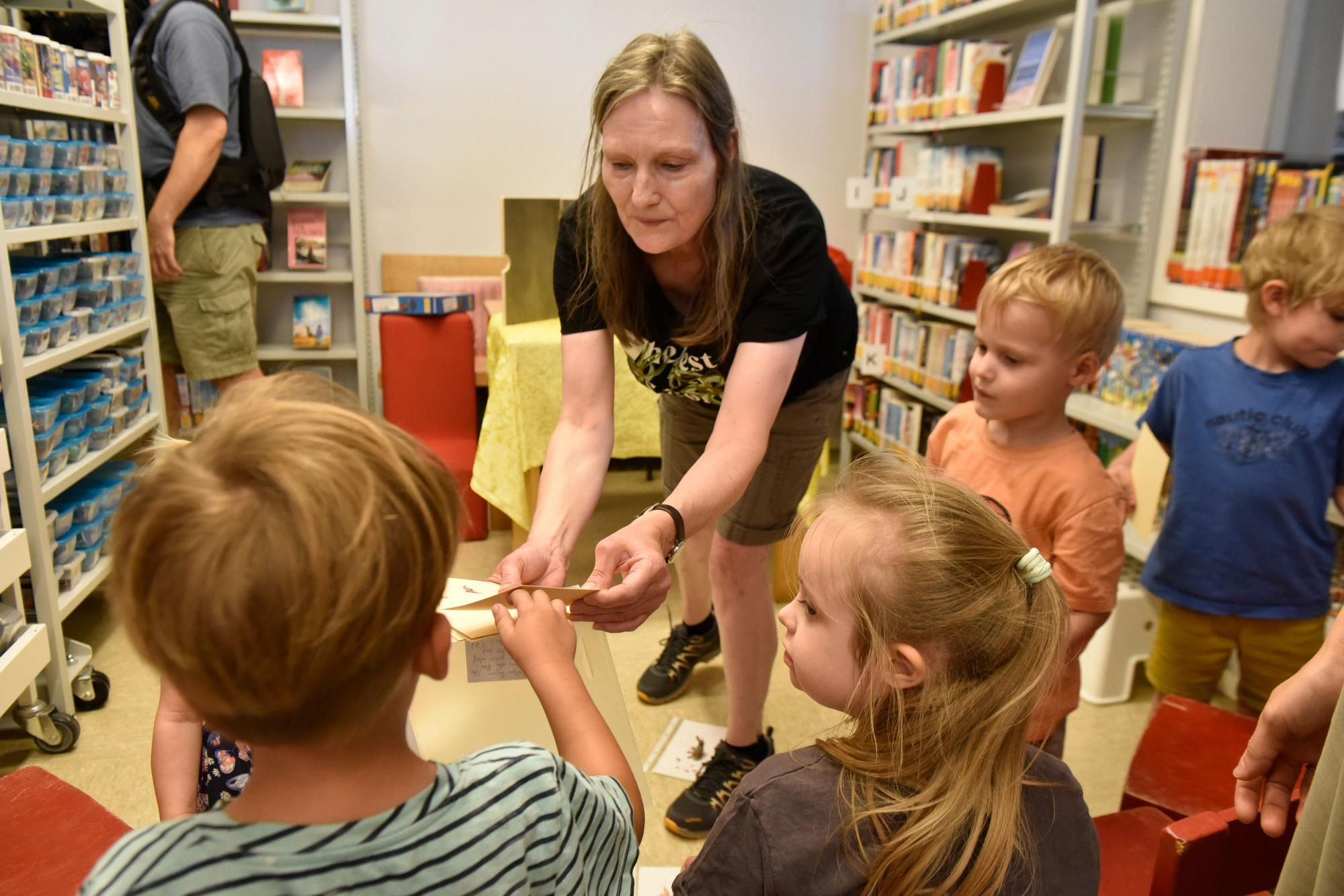 Das Foto zeigt eine Gruppe von Kindern beim Spielen mit einer Frau in den Räumen der Bücherei.
