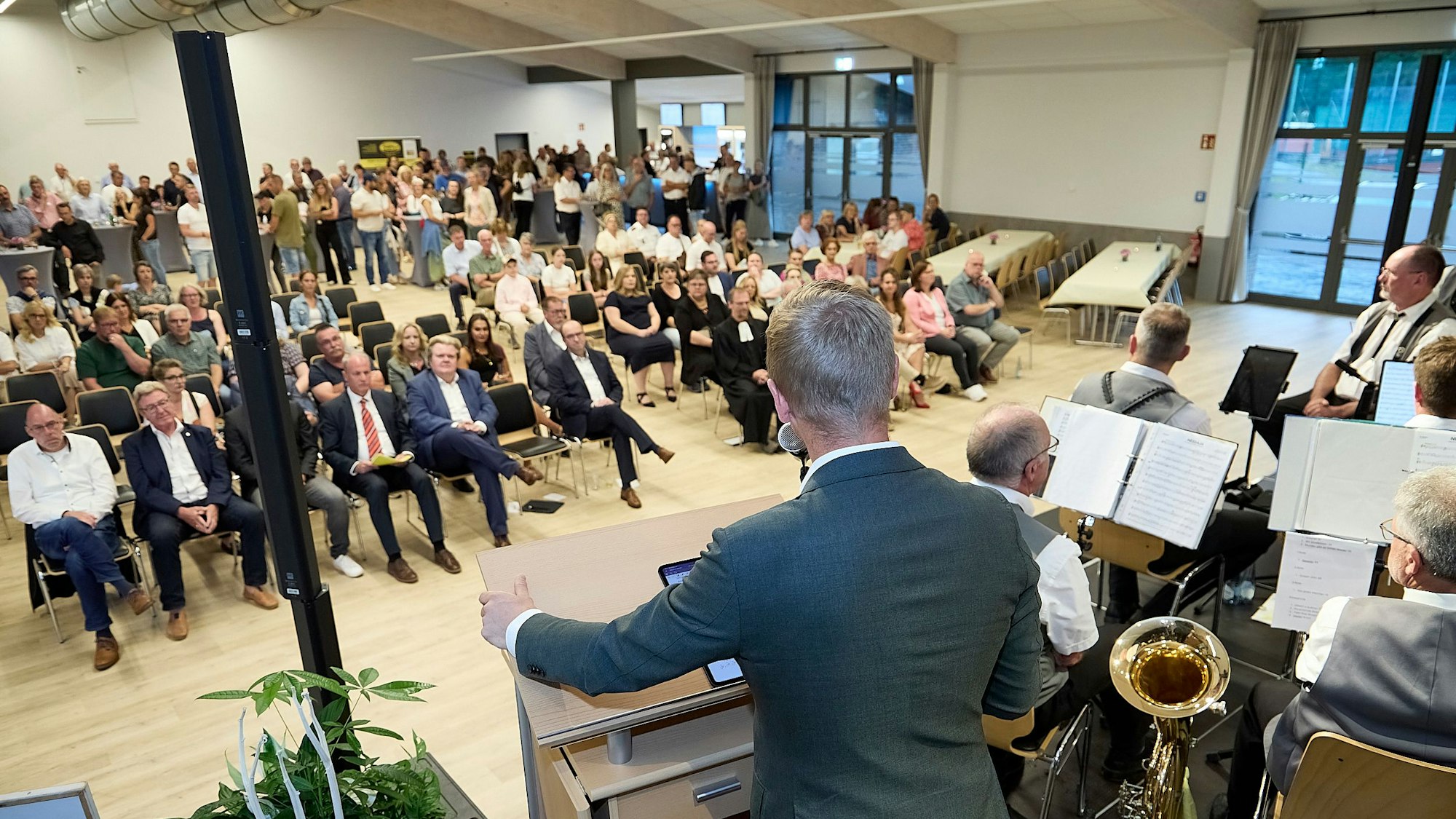 Markus Ramers steht an einem Rednerpult und spricht zu einem Publikum, das auf Stühlen vor einer Bühne sitzt.