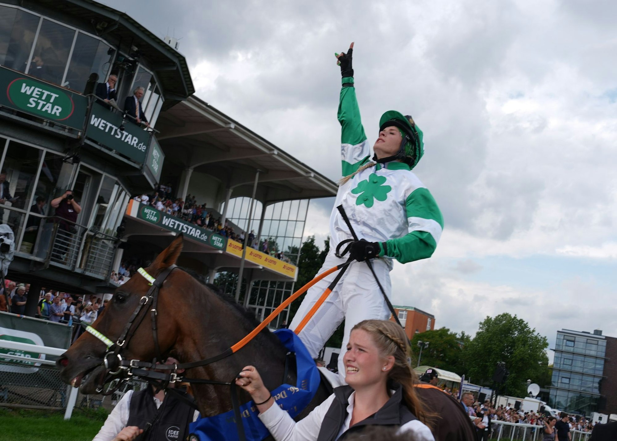 Erinnerung an ihren Vater: Nina Baltromei zeigt nach ihrem historischen Sieg beim deutschen Galopp-Derby mit dem Zeigefinger gen Himmel.