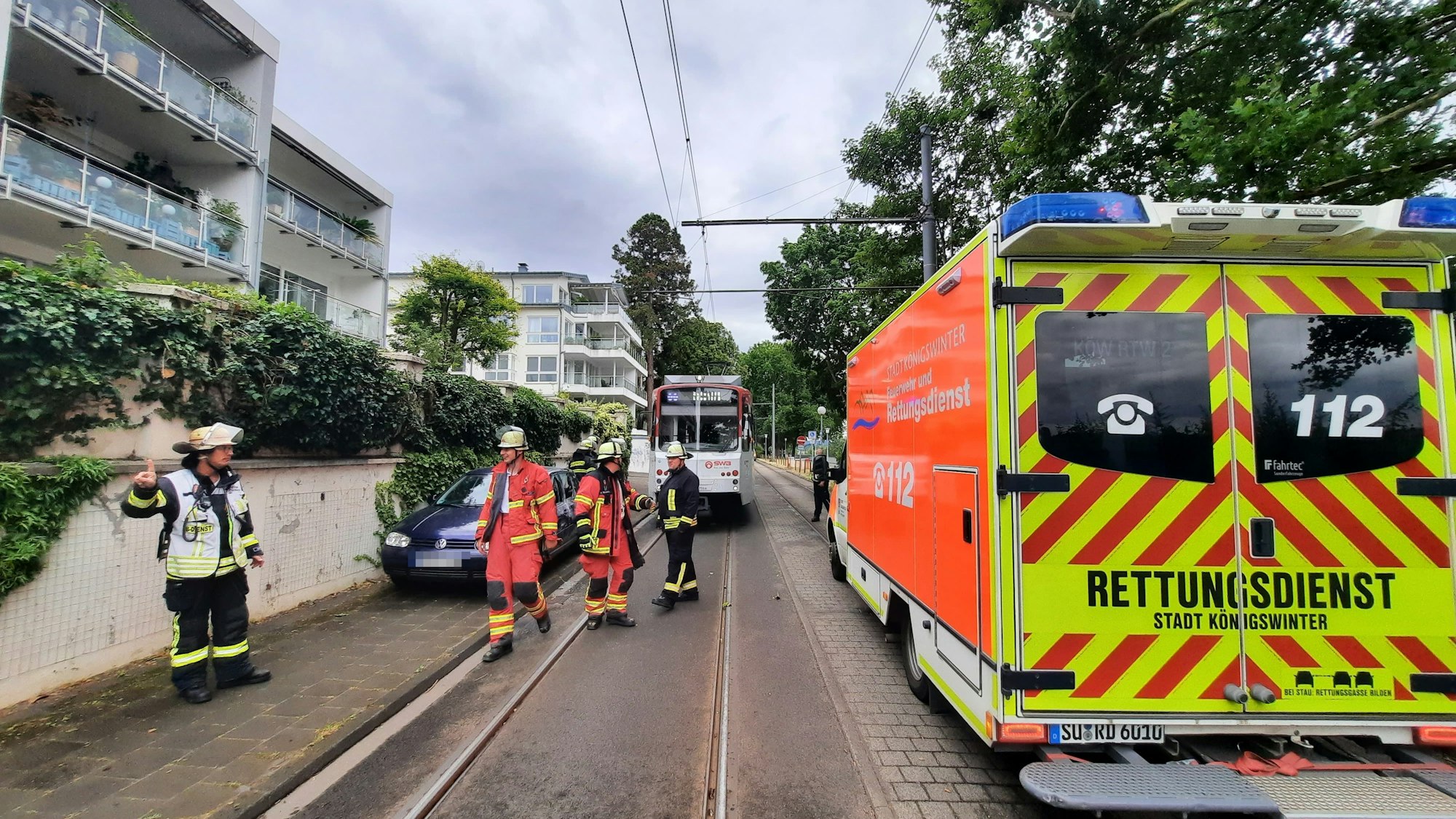 Ein Rettungswagen auf der Bahntrasse in Königswinter, im Hintergrund ein Pkw und die Stadtbahn.
