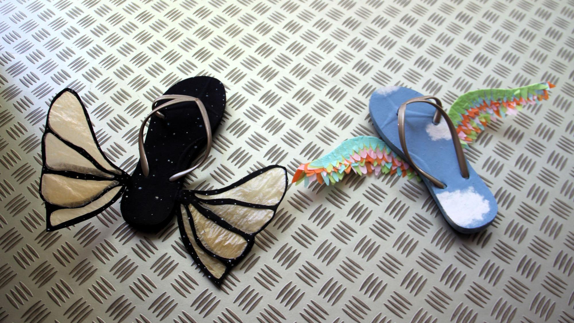 Auf einer Stahlplatte liegen Flip-Flops, an die Flügel angebracht wurden.