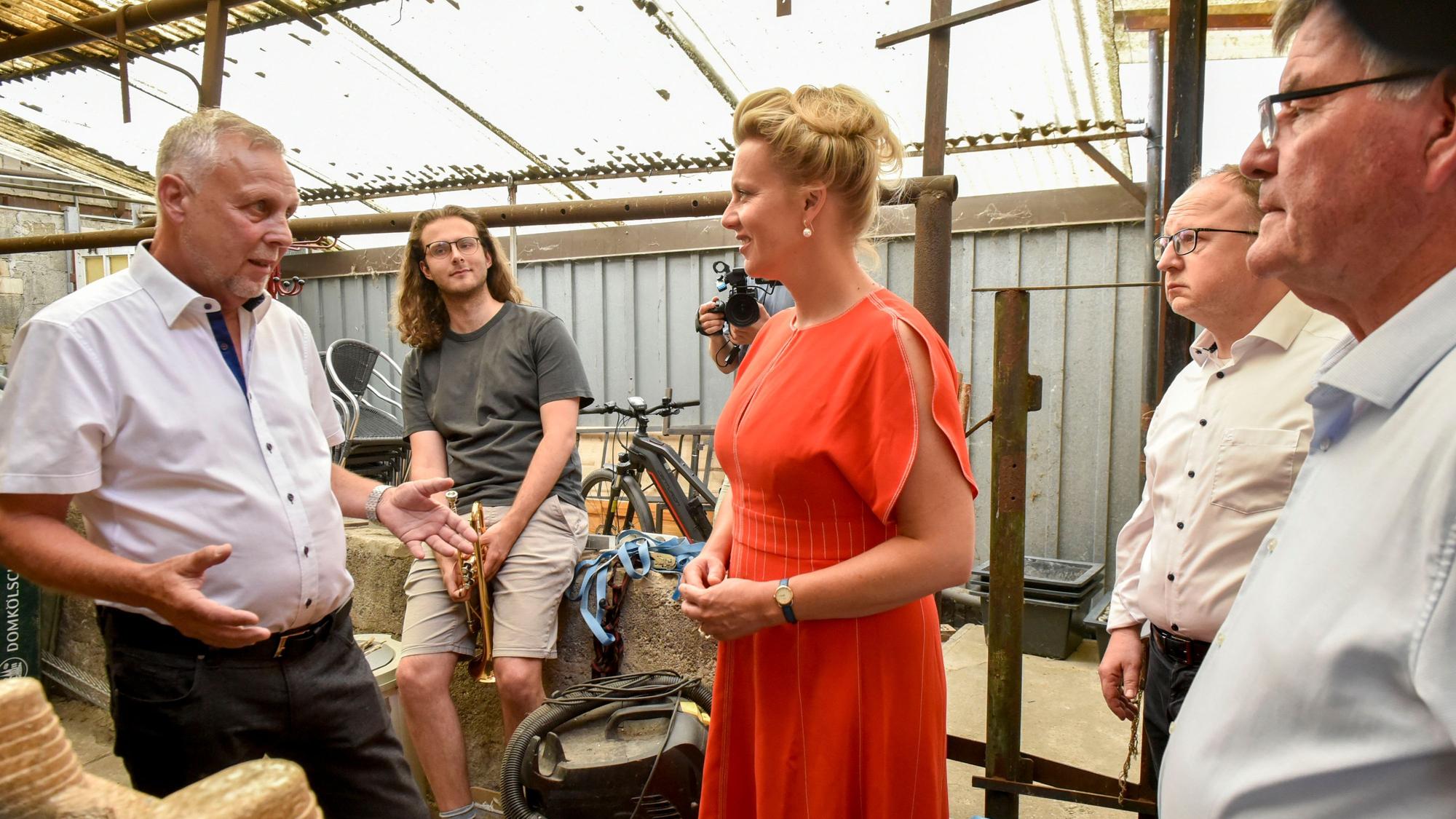 Das Foto zeigt die Ministerin im orangefarbenen Kleid mit Vorstandsmitgliedern des Quartiersvereins im Bereich hinter der Bühne des Kulturgasthauses.