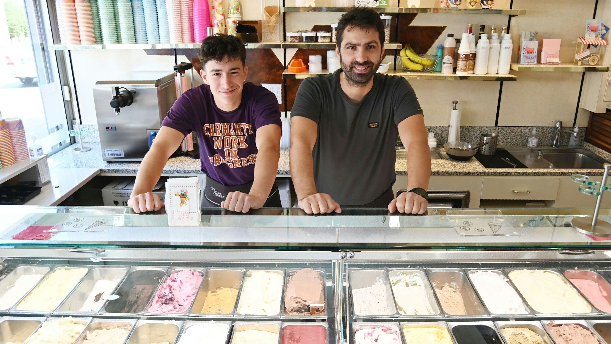 Zwei Männer in einer Eisdiele mit diversen Sorten.