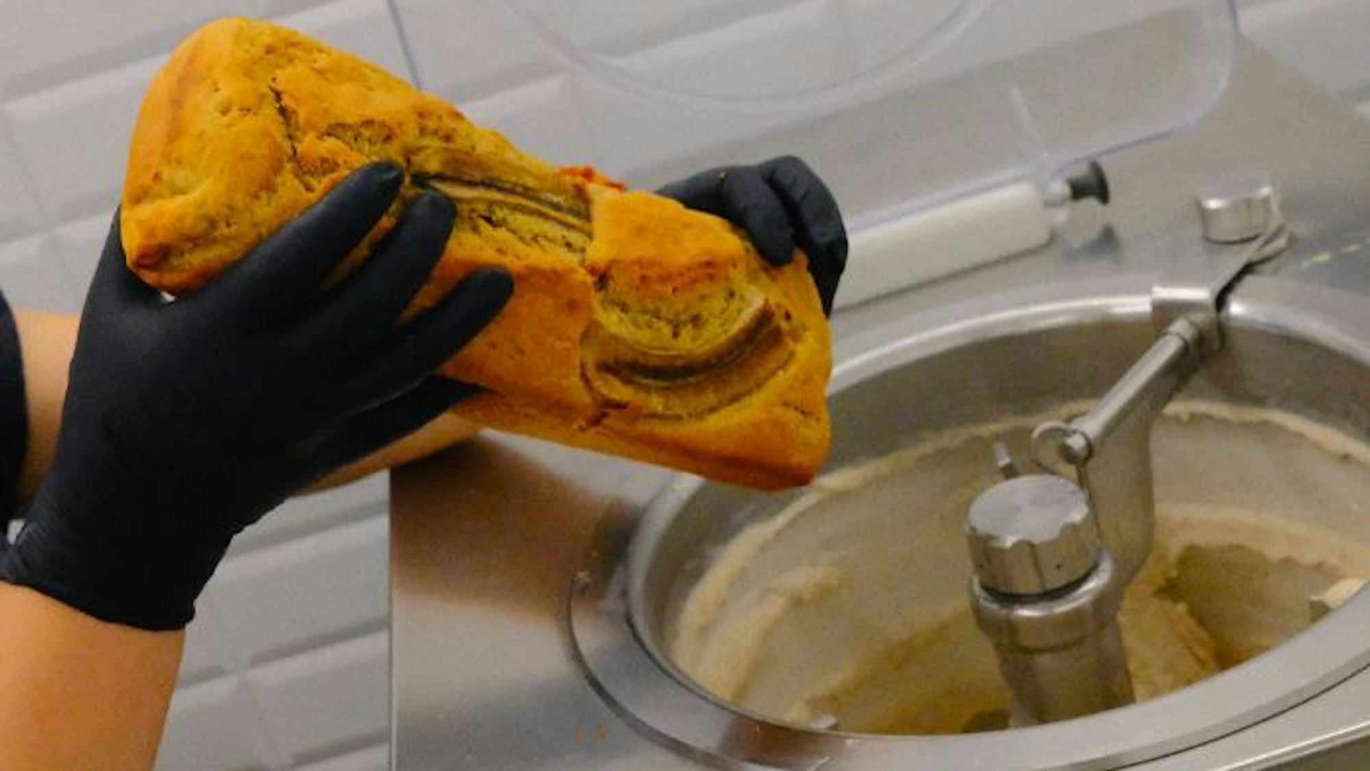 Eine Person hält ein Bananenbrot über eine Eismaschine.