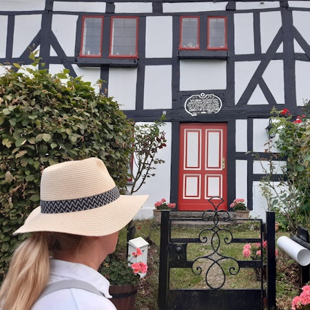Eine Frau blickt auf die Fassade eines Fachwerkhauses.