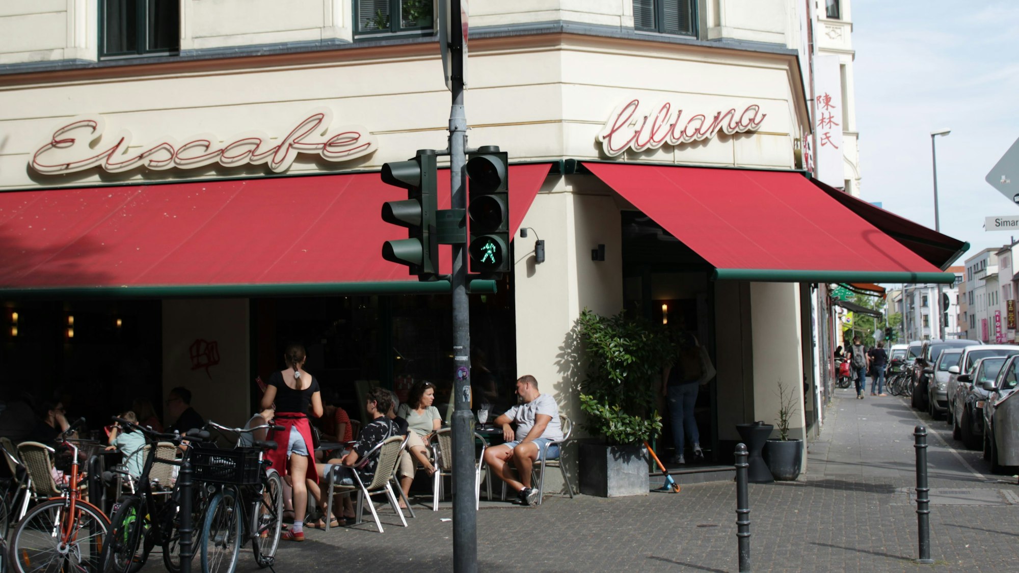 Ein Eiscafé an einer Straßenecke, wo mehrere Leute draußen sitzen.