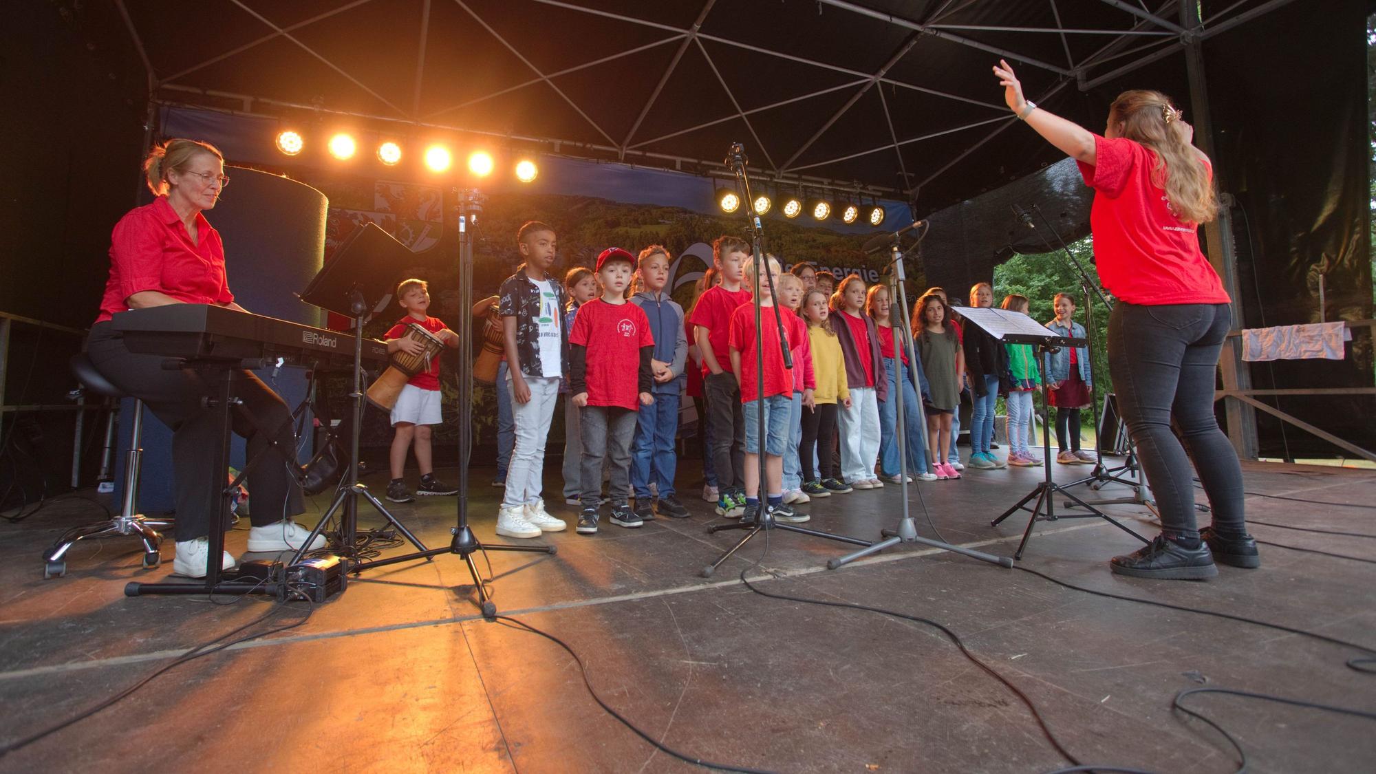 Ein Kinderchor auf einer Bühne.