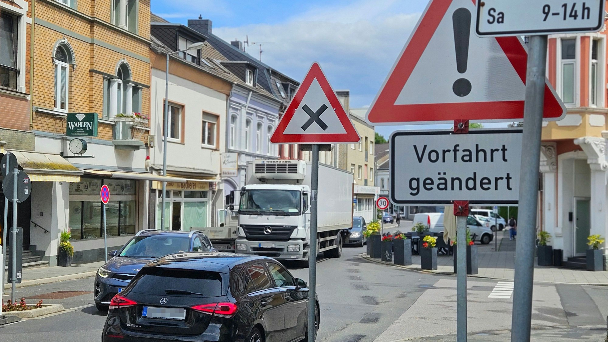 Zu sehen ist eine Kreuzung mit Fahrzeugen und mehreren Verkehrsschildern in der Bedburger Innenstadt.