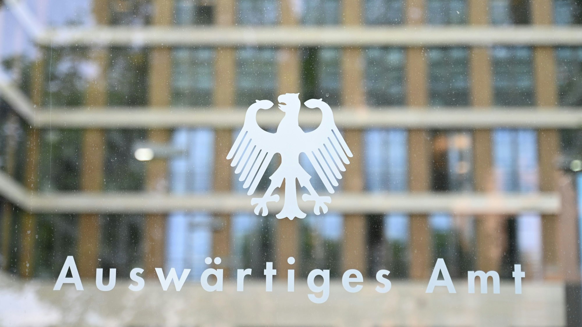 ARCHIV - 27.05.2025, Berlin: Der Bundesadler und der Schriftzug «Auswärtiges Amt» sind an einer Glasscheibe an einem Eingang zum Auswärtigen Amt zu sehen. (zu dpa: «Deutsches Botschaftspersonal aus Teheran ins Ausland verlegt») Foto: Katharina Kausche/dpa +++ dpa-Bildfunk +++