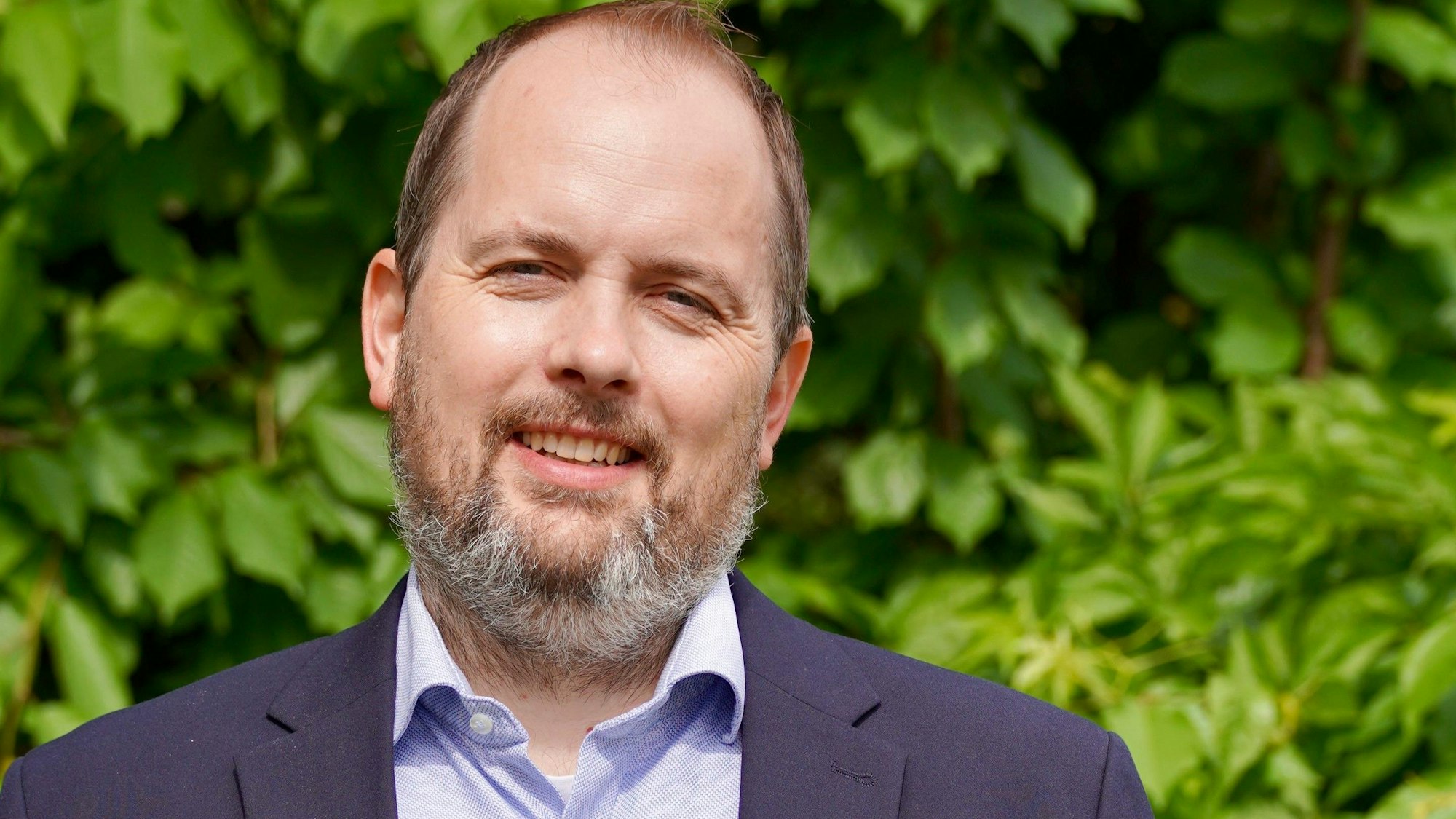 Ein Mann mit Bart lächelt in die Kamera.