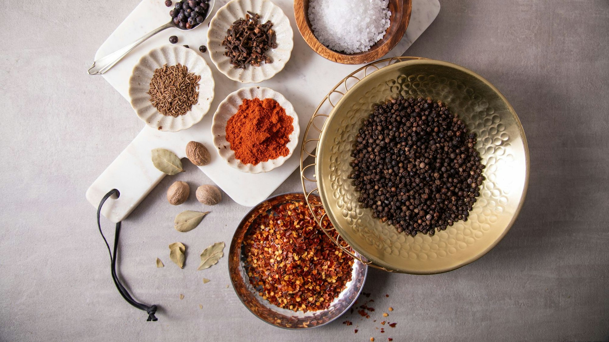 Zur Grundausstattung in der Küche gehören Salz, schwarzer Pfeffer, Chili-Flocken, Paprika edelsüß oder geräuchert, Kümmel, Nelken, Wachholderbeeren, Lorbeer und Muskatnuss.