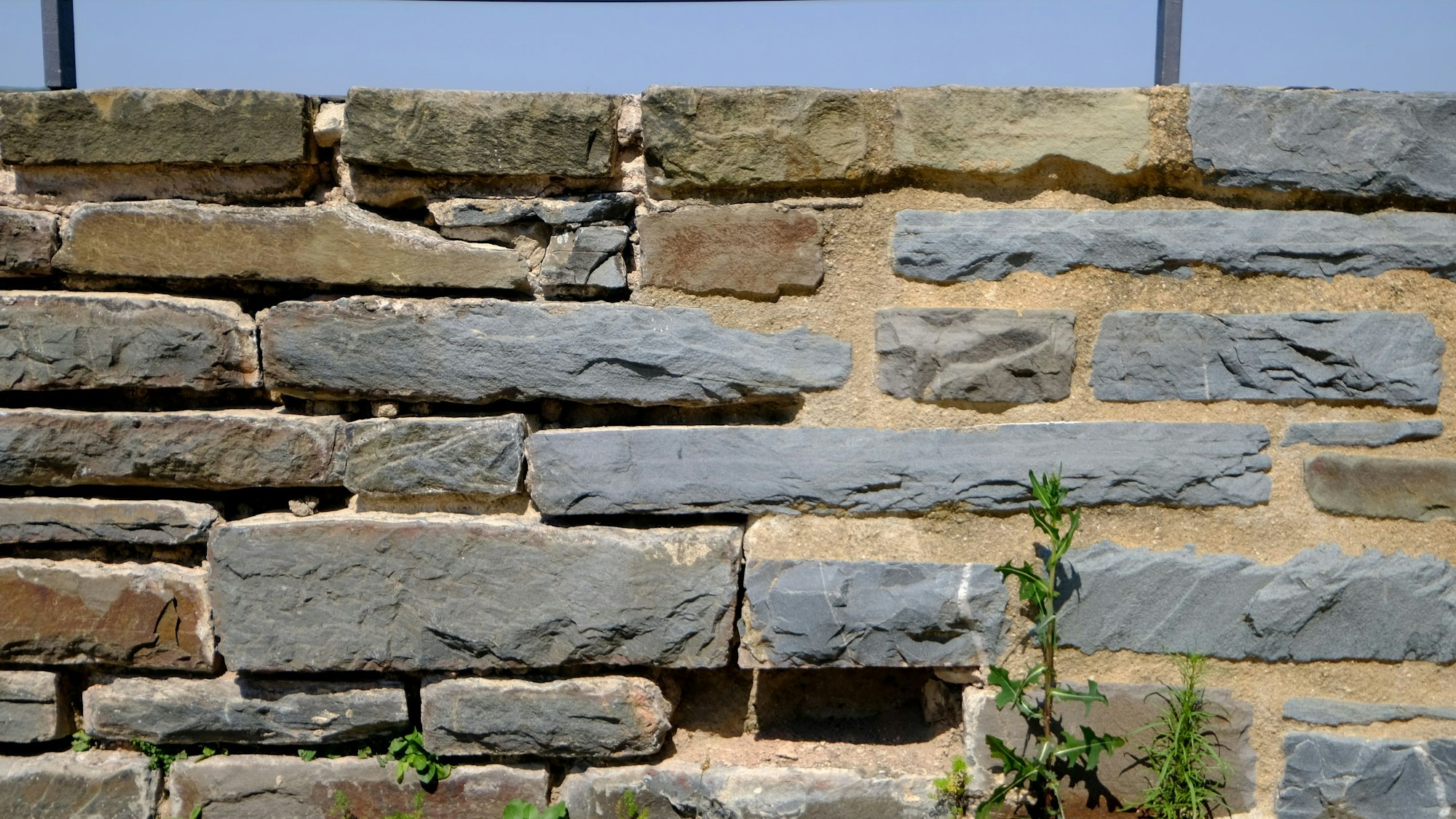 Das Bild zeigt eine Bruchsteinmauer. Im rechten Teil wurden die Fugen neu mit einem Spezialmörtel ausgefüllt.