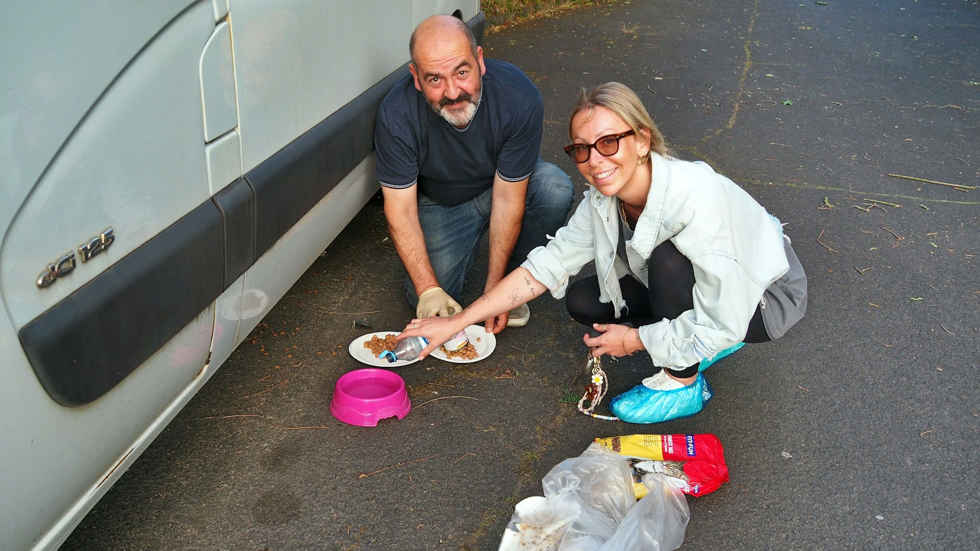 Ein Mann und eine Frau füllen Futter in Näpfe.