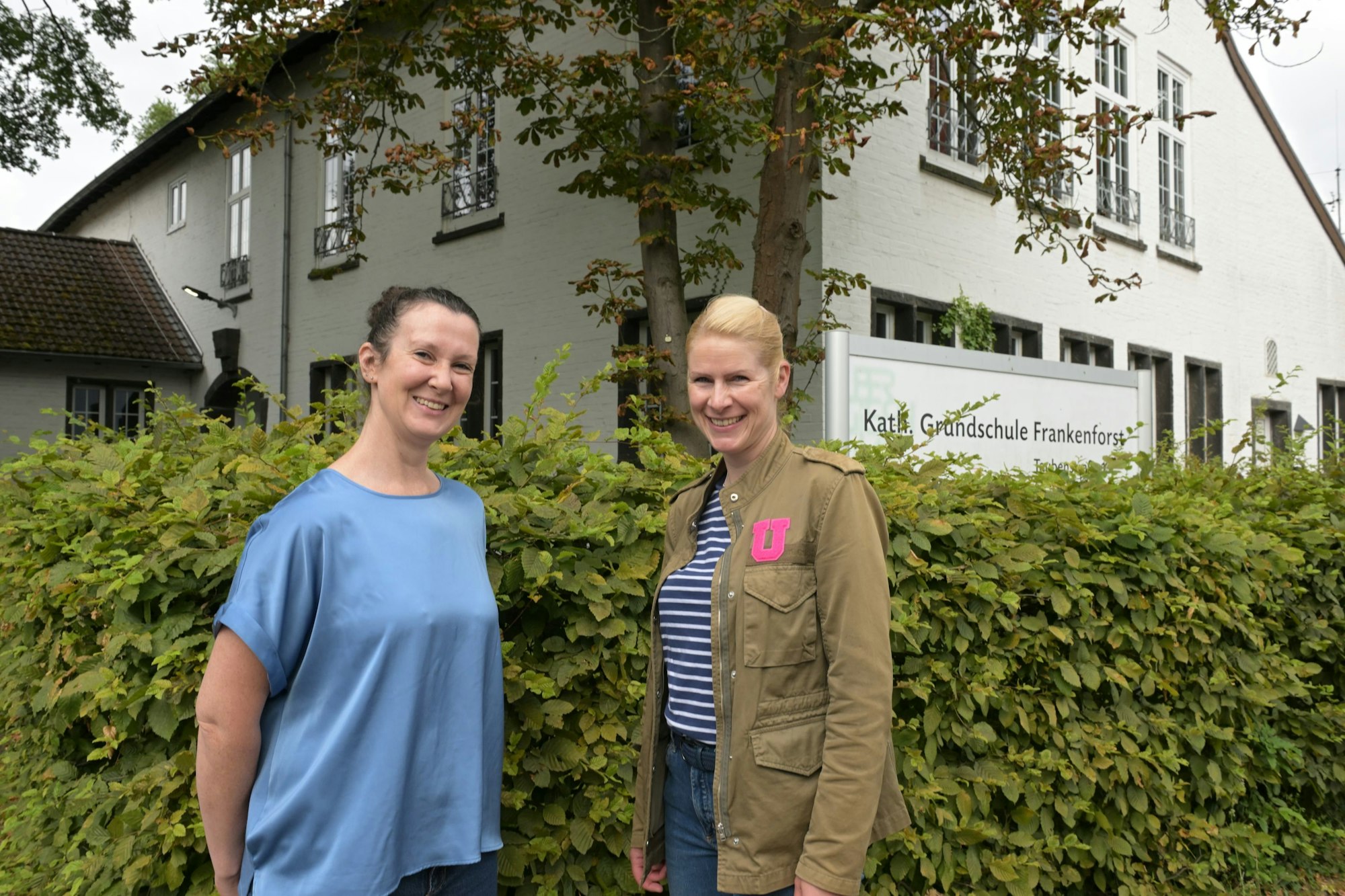 Die beiden Elternvertreterinnen stehen nebeneinander vor dem Schulgebäude.