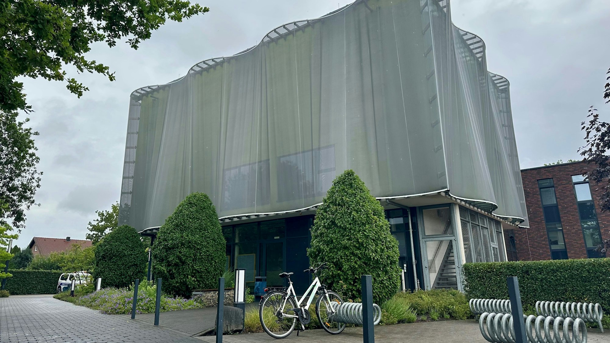 Zu sehen ist ein Gebäude, das wirkt, als wäre es von einem grauen eisernen Umhang verdeckt.