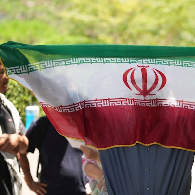 Ein Mann hält eine iranische Flagge während einer Kundgebung mit der Forderung, den Krieg zwischen Israel und dem Iran zu beenden