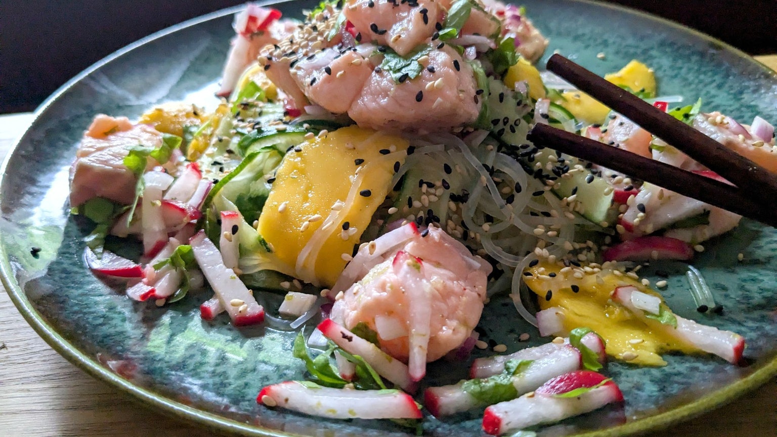Der Glasnudelsalat mit Lachs-Ceviche wird mit gerösteten weißen und schwarzen Sesamkörnchen getoppt.