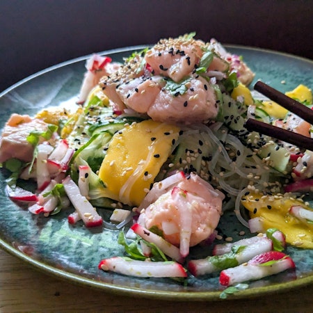 Der Glasnudelsalat mit Lachs-Ceviche wird mit gerösteten weißen und schwarzen Sesamkörnchen getoppt.
