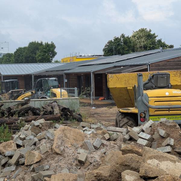 Das Foto zeigt Baufahrzeuge und Bauschutt vor dem Holzgebäude der Kita in Kalscheuren.