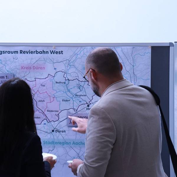 Eine Frau und ein Mann stehen vor einer Karte des Rheinischen Reviers.