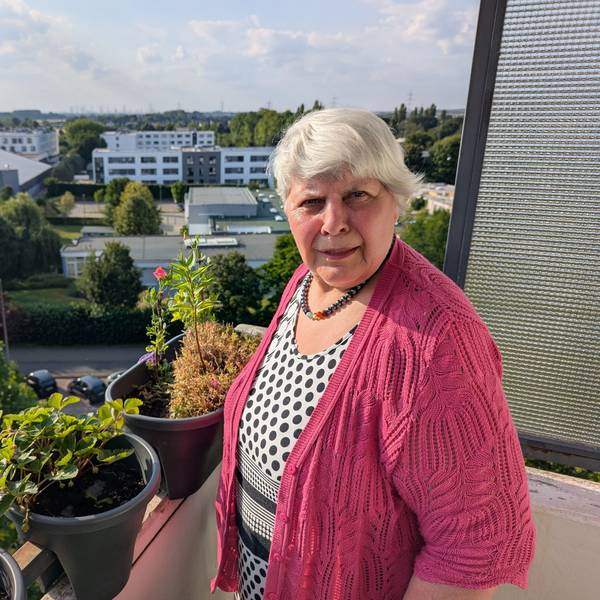 Das Foto zeigt eine Frau auf dem Balkon ihre Wohnung.