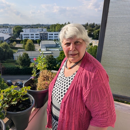 Das Foto zeigt eine Frau auf dem Balkon ihre Wohnung.