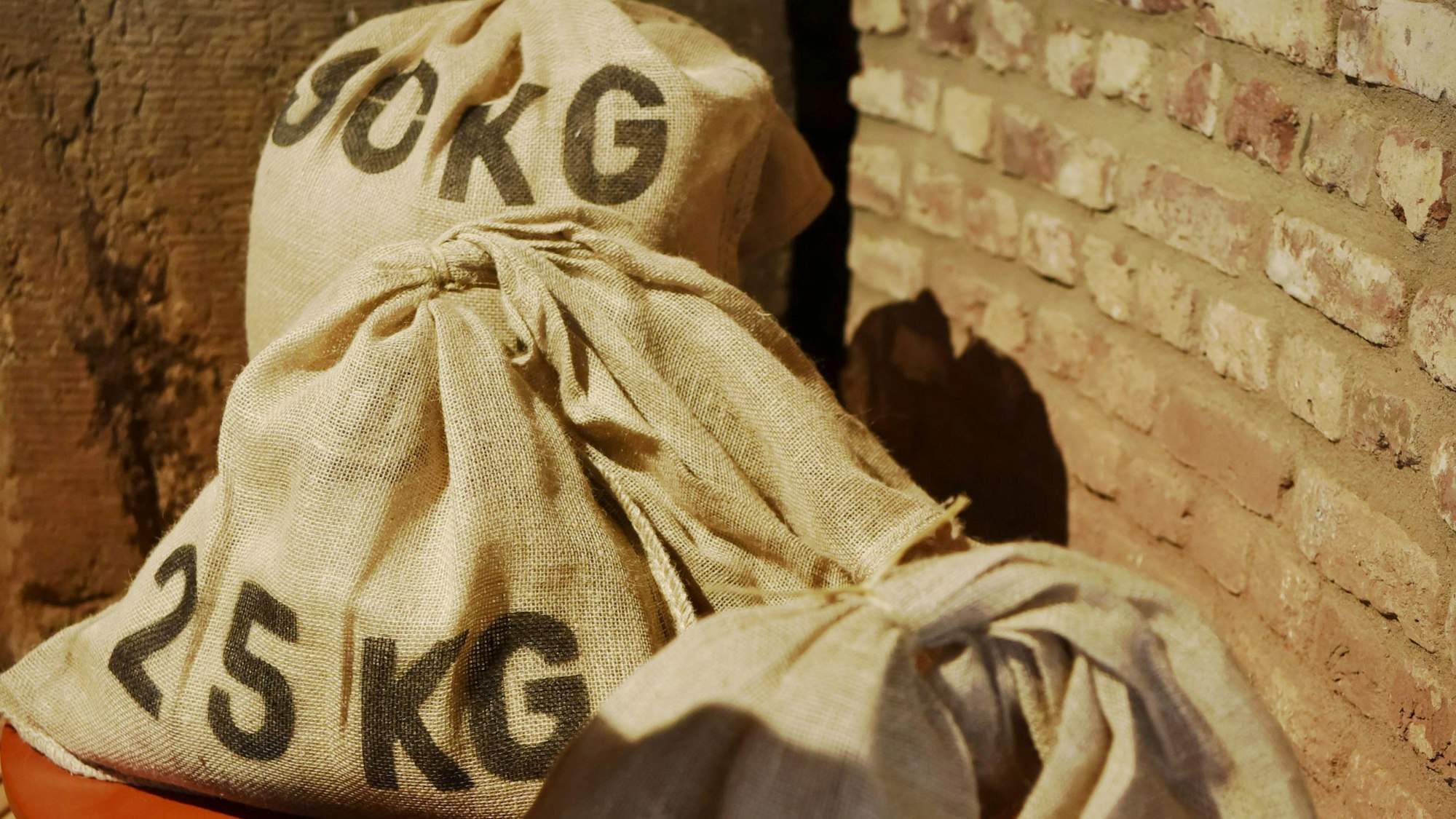 Drei Müllersäcke stehen vor einer Ziegelwand.