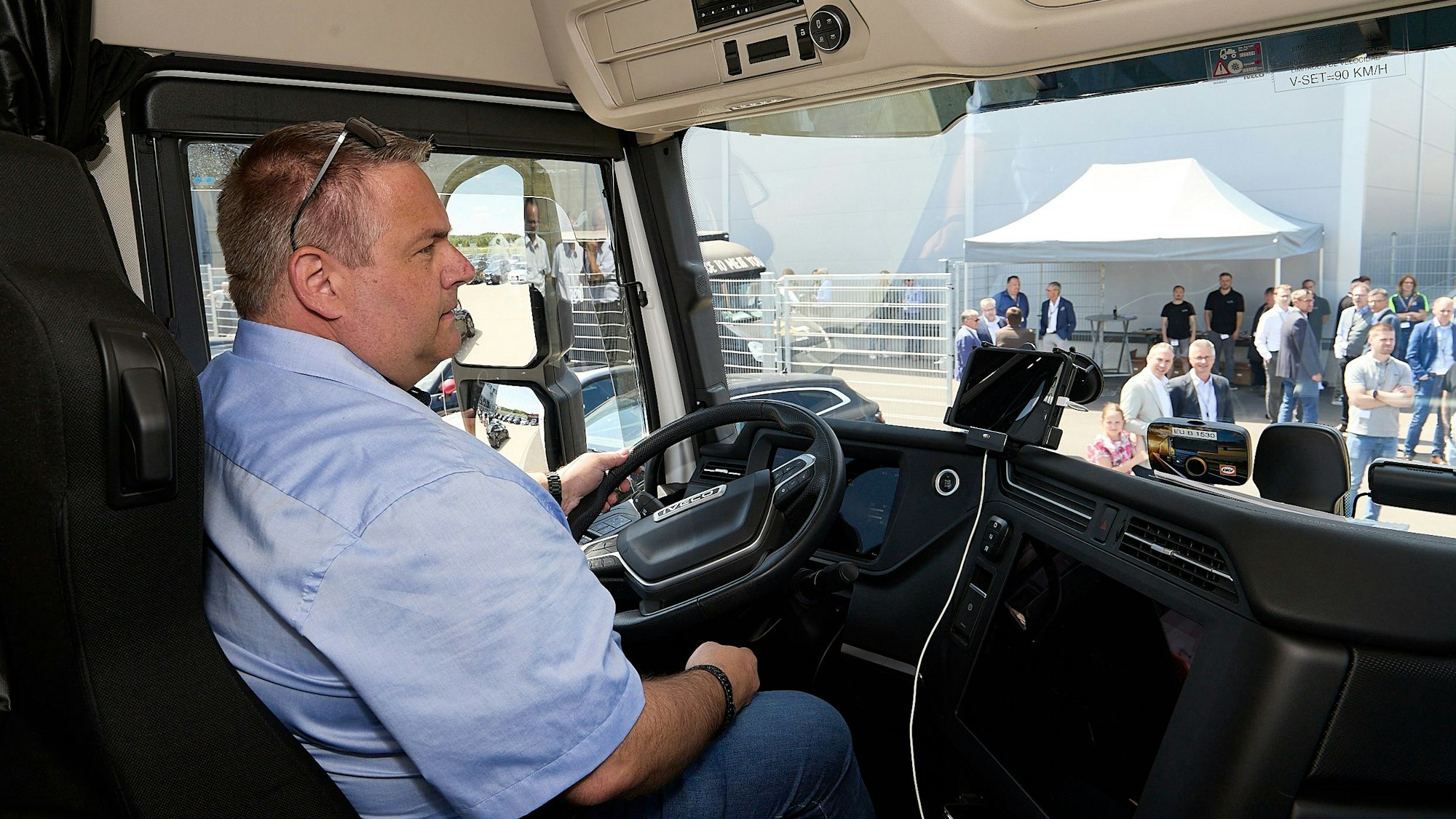 Fuhrparkleiter Daniel Kyll sitzt hinter dem Steuer des E-Trucks und hat die Sonnenbrille hochgeschoben.