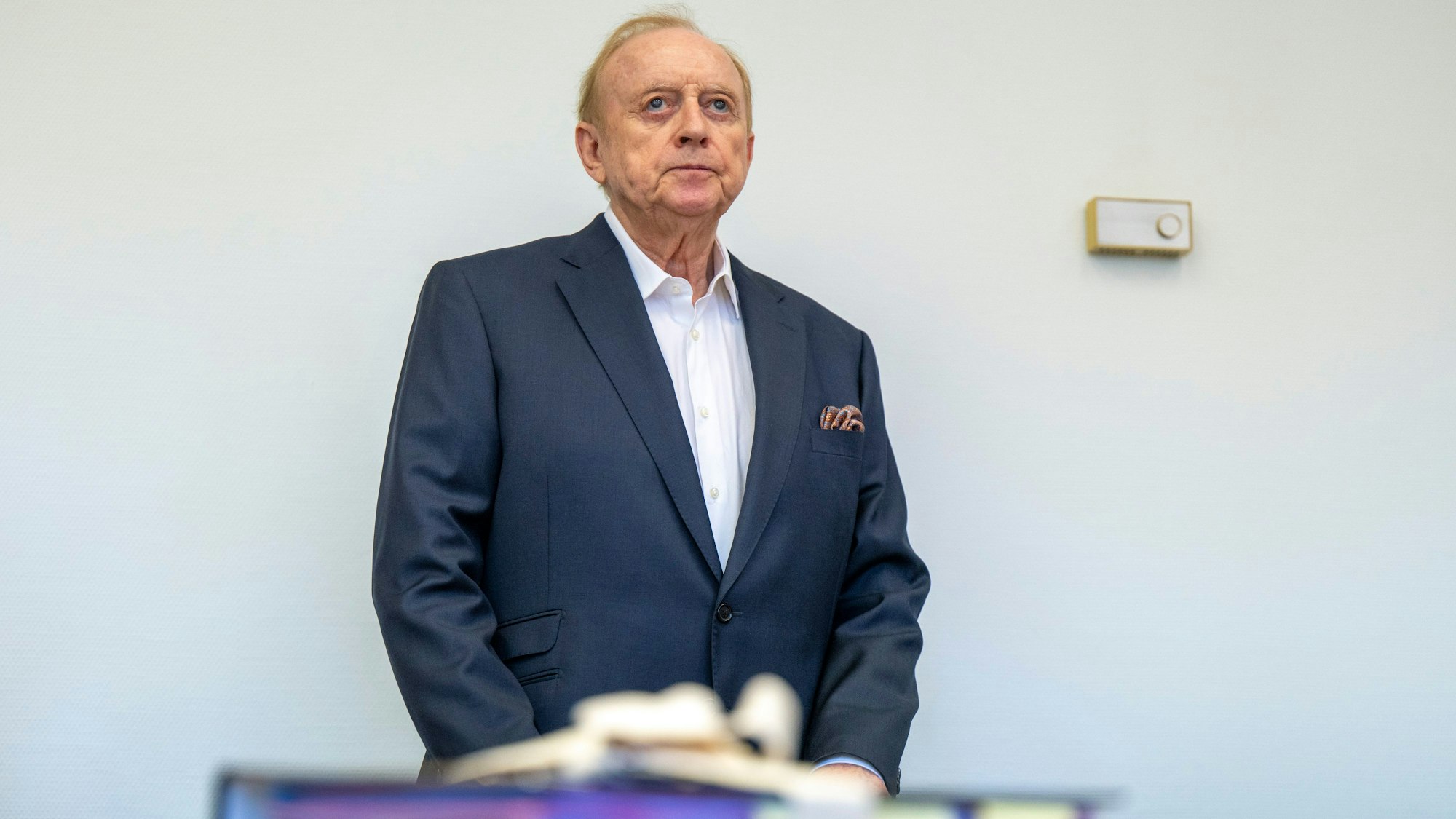 Alfons Schuhbeck steht im Gerichtssaal des Landgericht München I vor seinem Platz an der Anklagebank.