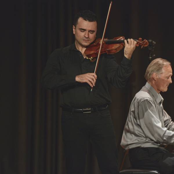 Zwei Musiker auf der Bühne – einer am Klavier und der andere mit Geige.