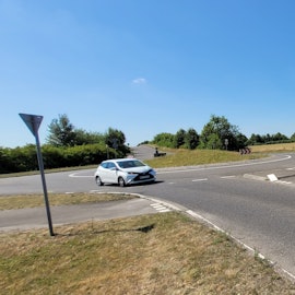 Ein Auto fährt in einem Kreisverkehr, in der Mitte stehen Fahnen.