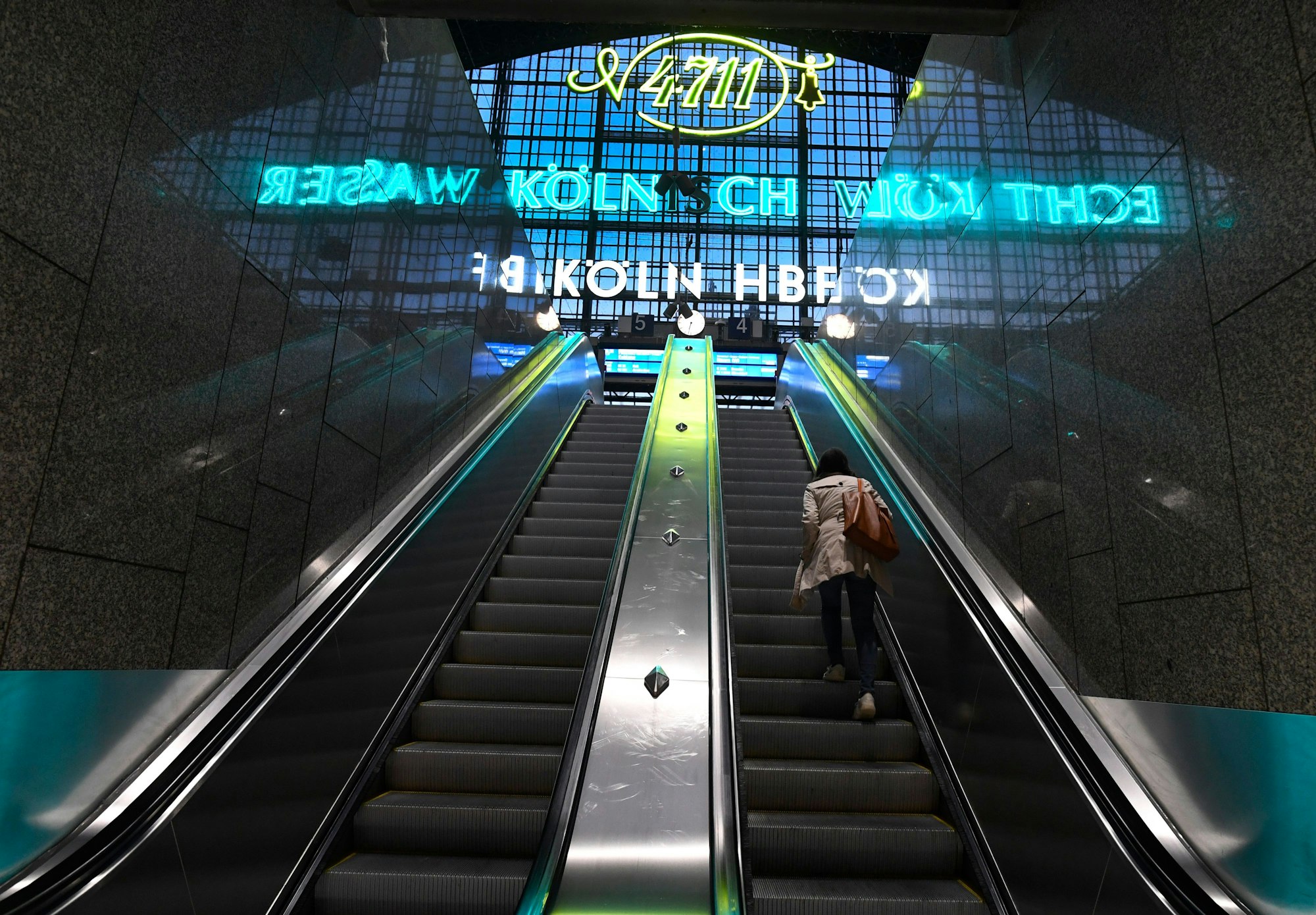 Köln: Eine Reisende steht im Kölner Hauptbahnhof auf einer Rolltreppe.