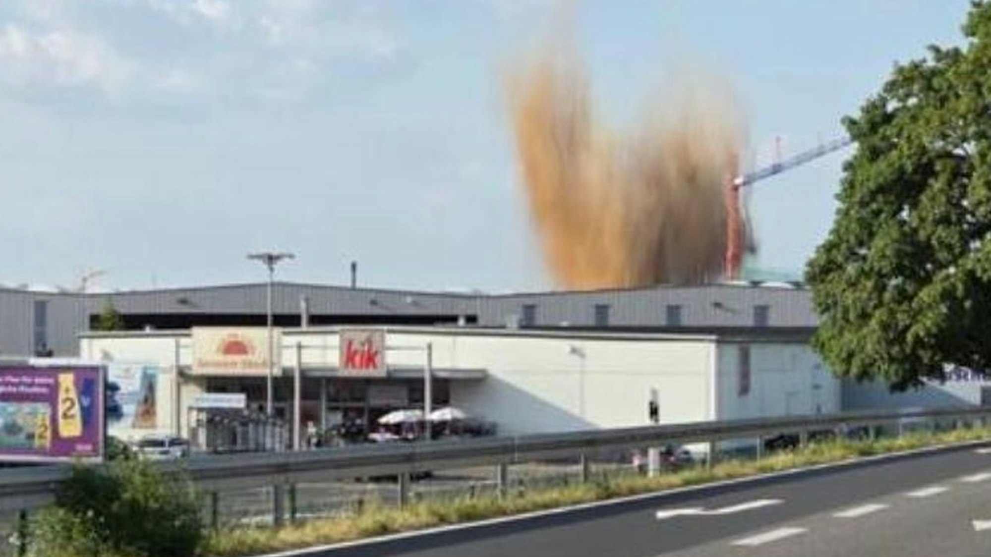 Hinter mehreren Gebäuden im Euskirchener Gewerbegebiet ist das hochsteigende Erdreich während der Sprengung zu sehen.