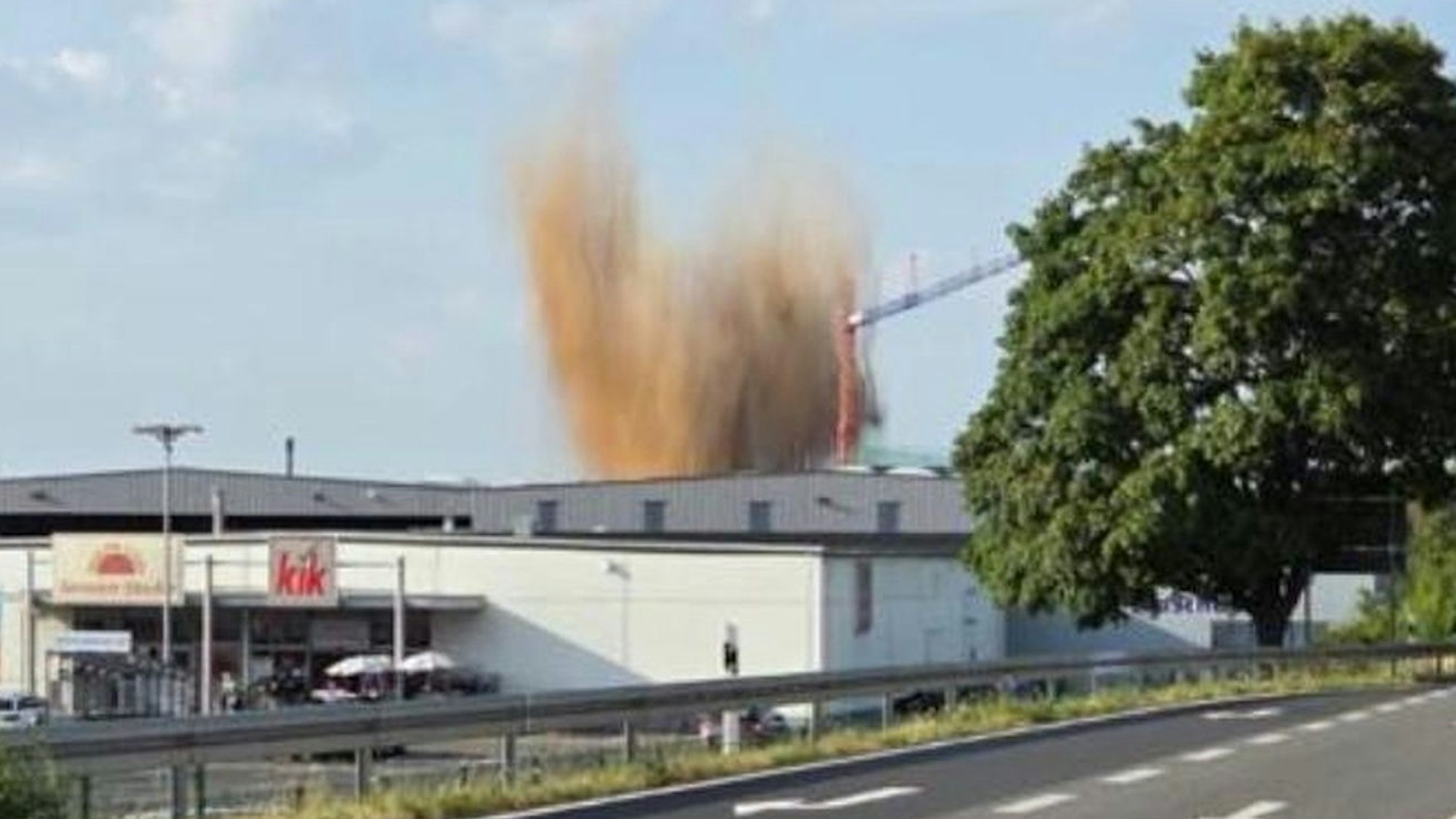 Hinter mehreren Gebäuden im Euskirchener Gewerbegebiet ist das hochsteigende Erdreich während der Sprengung zu sehen.