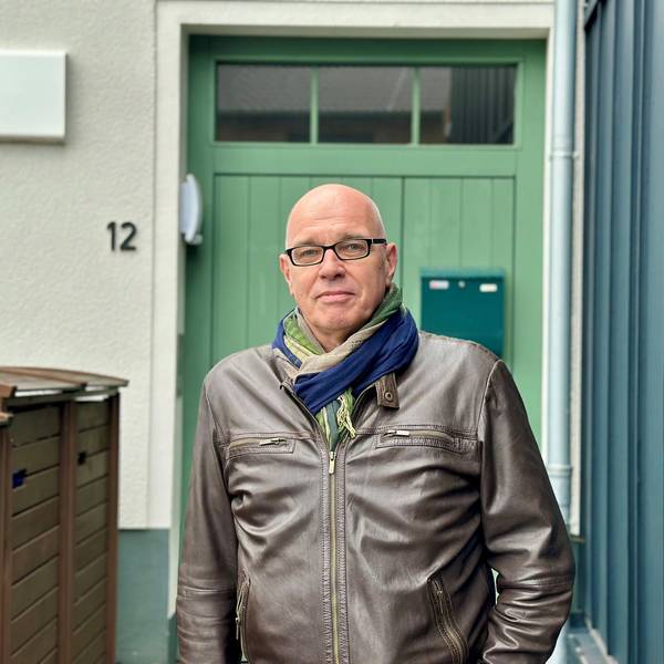 Ein Mann steht vor einer grünen Tür.